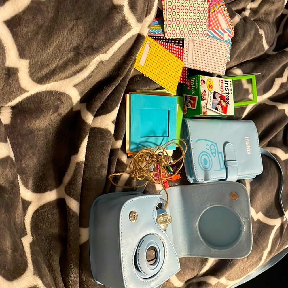 A instax camera with a case, film, film stickers, film frames